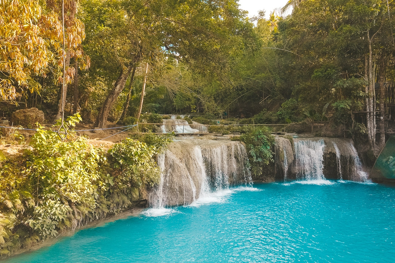 Stunning turquoise waterfall with silky water effect surrounded by lush tropical vegetation