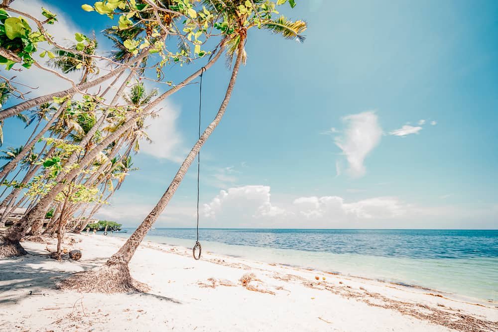 Paliton Beach with white sand and palm trees at sunset